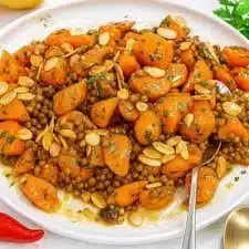 Roasted carrot and lentil bowl topped with greens and spices
