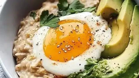 Bowl of savory avocado oatmeal topped with herbs and spices