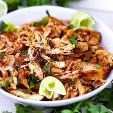 Plate of shredded chicken served with vegetables and spices