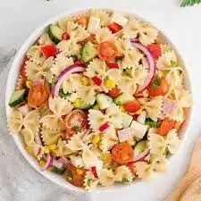 Colorful summer pasta salad with vegetables and dressing in a bowl.
