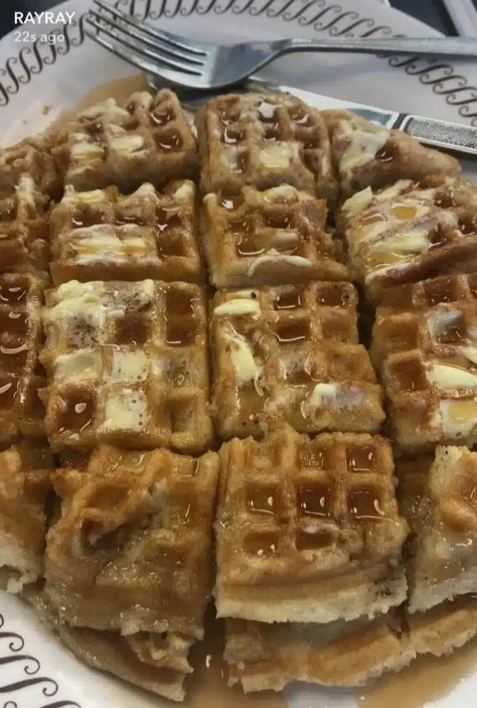 Golden brown waffles topped with syrup and berries on a plate