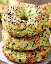 Homemade zucchini bagels with herbs and toppings on a wooden board