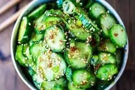 Asian Cucumber Salad topped with sesame dressing and garnished with herbs