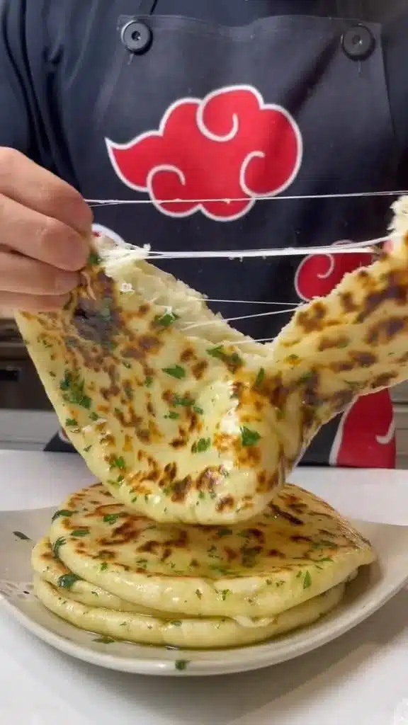 Cheese Stuffed Garlic Naan with herbs and garlic on the side.