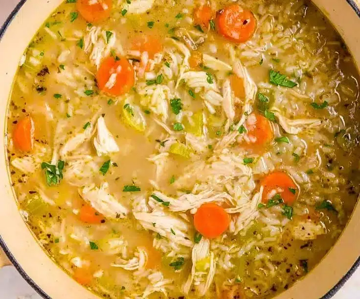 Creamy Chicken & Rice Soup in a bowl with fresh herbs and ingredients.
