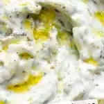 Bowl of creamy tzatziki sauce with fresh herbs and cucumber slices