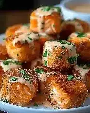 Crispy bang bang salmon bites served on a plate, garnished with sauce.