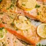 Garlic butter baked salmon garnished with herbs, served on a plate