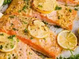 Garlic butter baked salmon garnished with herbs, served on a plate