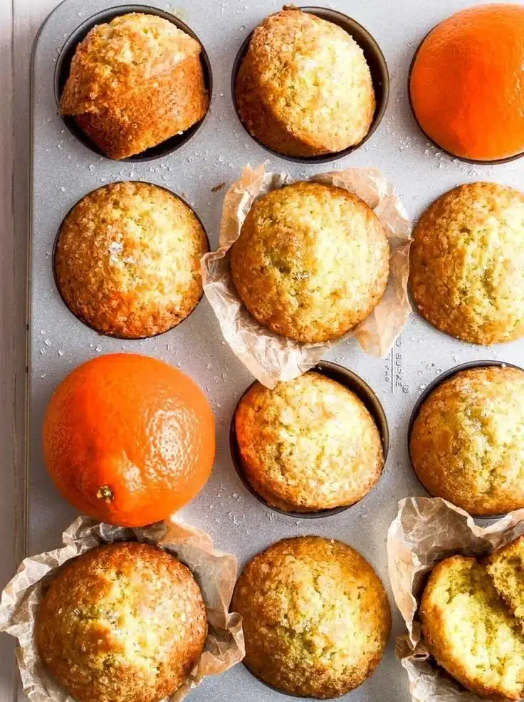Freshly baked orange and cardamom muffins on a wooden table