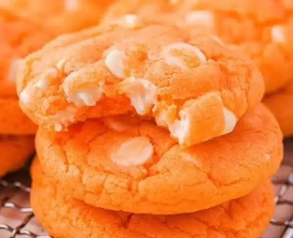 Freshly baked orange creamsicle cookies with vibrant orange frosting.
