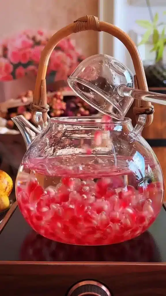 Cup of Pomegranate Rose Black Tea with rose petals and pomegranate seeds.