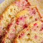 Sliced quick lemon rhubarb bread on a wooden cutting board