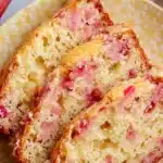 Moist and tangy homemade lemon rhubarb bread sliced on a wooden board.