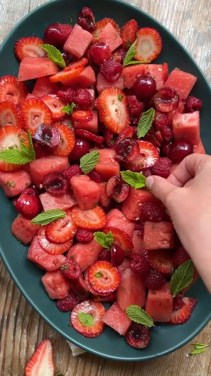 Delicious watermelon salad with fresh fruits and mint leaves served in a bowl.