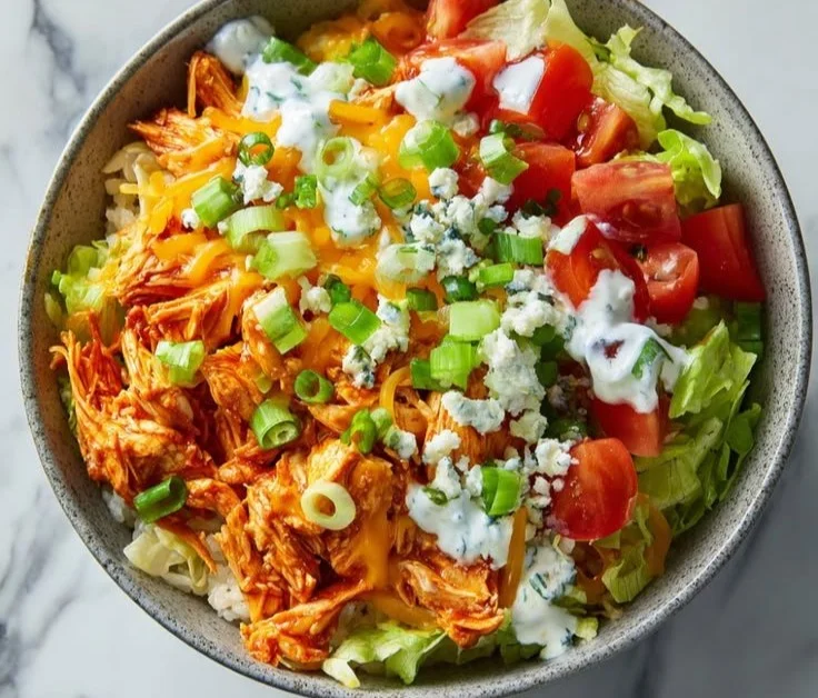 Buffalo Chicken Bowl topped with fresh vegetables and creamy sauce