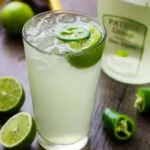 A refreshing Coconut Lime Drink served in a glass with ice and lime slices.