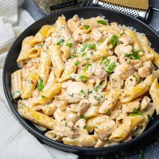 Creamy chicken pasta dish served in a bowl with herbs and cheese on top