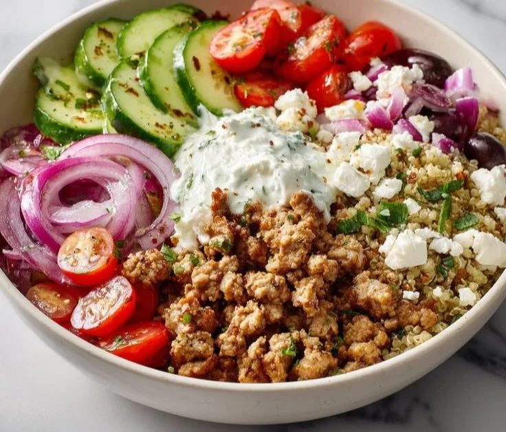 Healthy Greek ground chicken bowls topped with fresh vegetables and herbs
