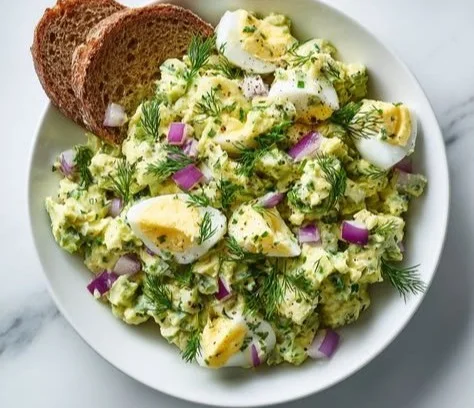 Herby avocado egg salad in a bowl garnished with herbs