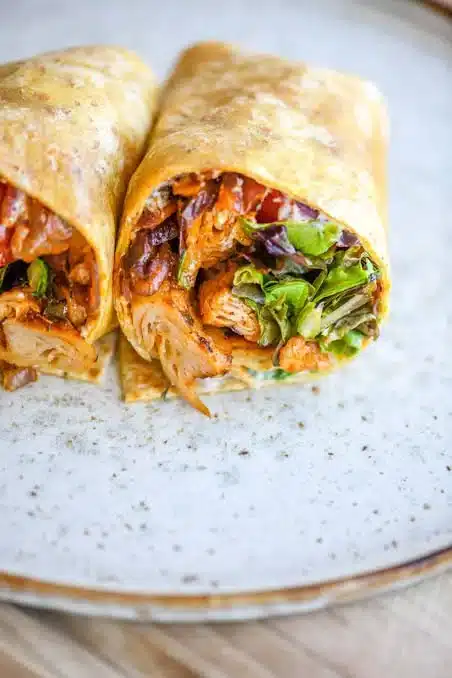 High protein chicken wrap with fresh vegetables and sauces on a plate