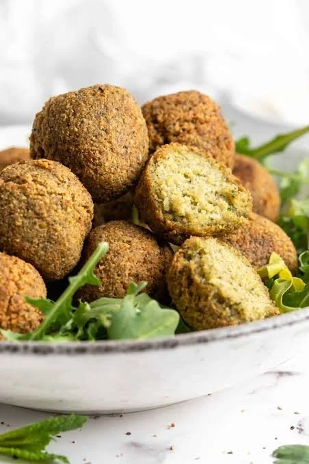Plate of homemade falafel served with fresh vegetables and sauce.