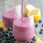 Delicious mango smoothie in a clear glass topped with fresh mango slices