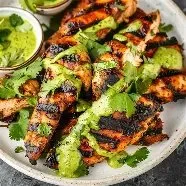Plate of Peruvian Chicken served with vibrant green sauce and fresh herbs.