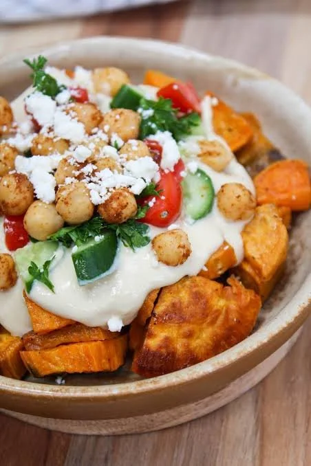 Roasted Sweet Potato & Chickpea Greek Bowl topped with fresh herbs and sauces
