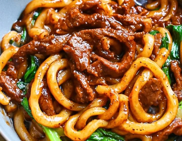 Delicious Beef Black Pepper Udon stir-fry served in a bowl with fresh vegetables