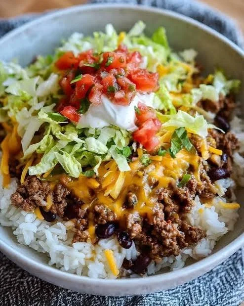 A delicious taco rice bowl topped with fresh ingredients and spices.