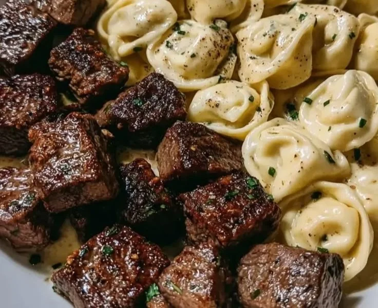 Delicious buttery steak tortellini served on a plate with fresh herbs