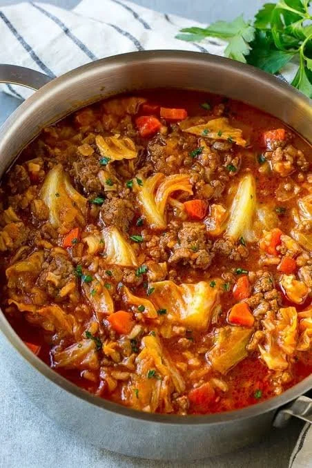 Bowl of cabbage roll soup with ground beef served with fresh herbs
