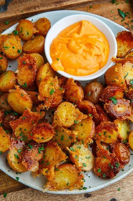 Crispy Parmesan potatoes served hot, garnished with herbs and spices.