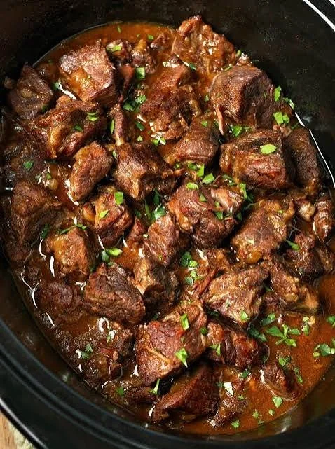 Crockpot garlic butter beef tips served with garlic and herbs