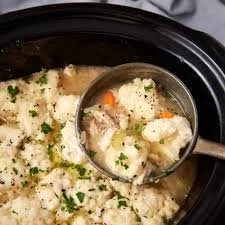 Bowl of easy crockpot chicken and dumplings with vegetables and herbs