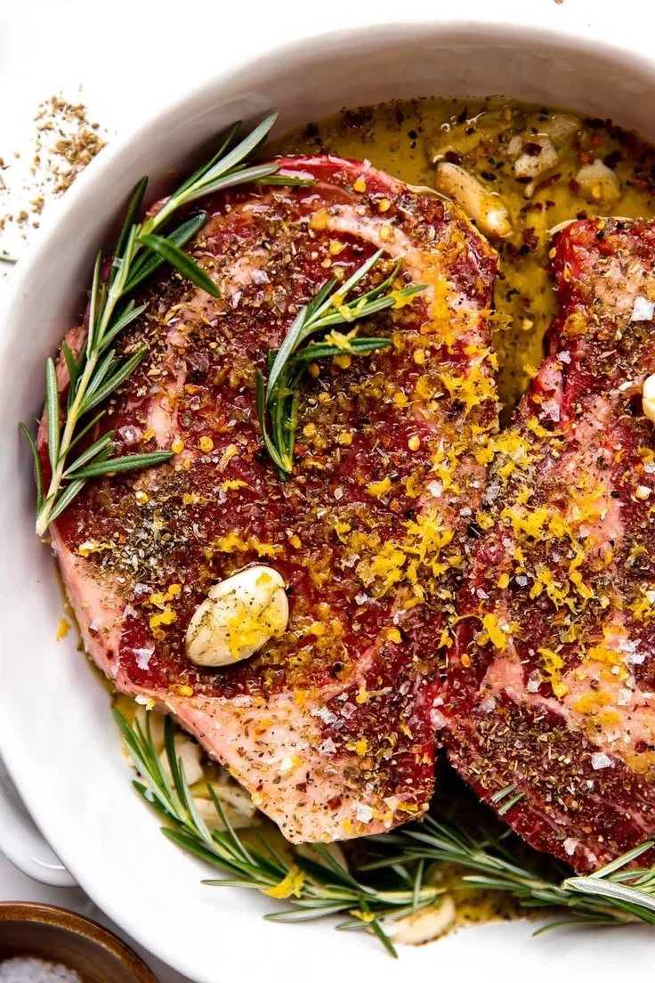 Grilled Tuscan steak garnished with lemon, garlic, and rosemary