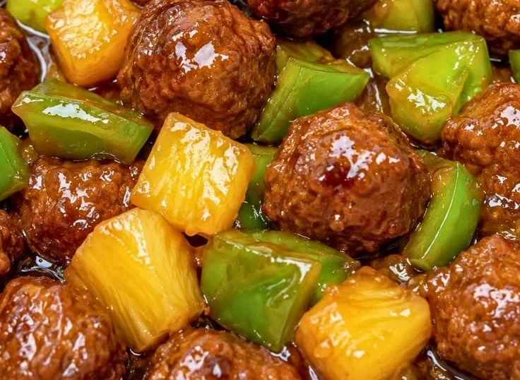 Plate of Healthy Hawaiian Meatballs garnished with pineapple and herbs