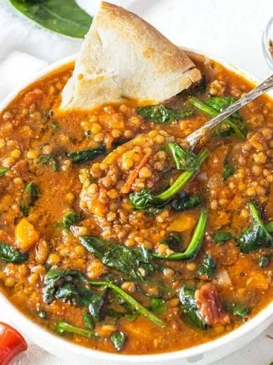 A bowl of high protein lentil stew with vegetables and spices