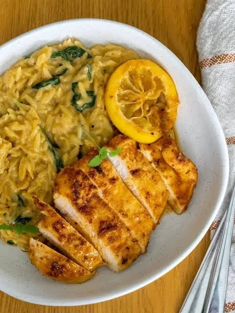 Creamy lemon chicken orzo dish in a pot garnished with herbs