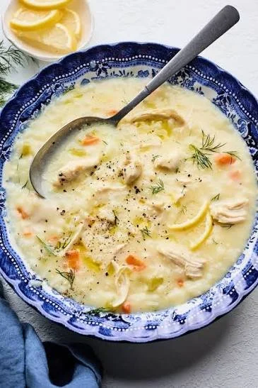 Bowl of Mediterranean Lemon Chicken Soup garnished with herbs and lemon slices