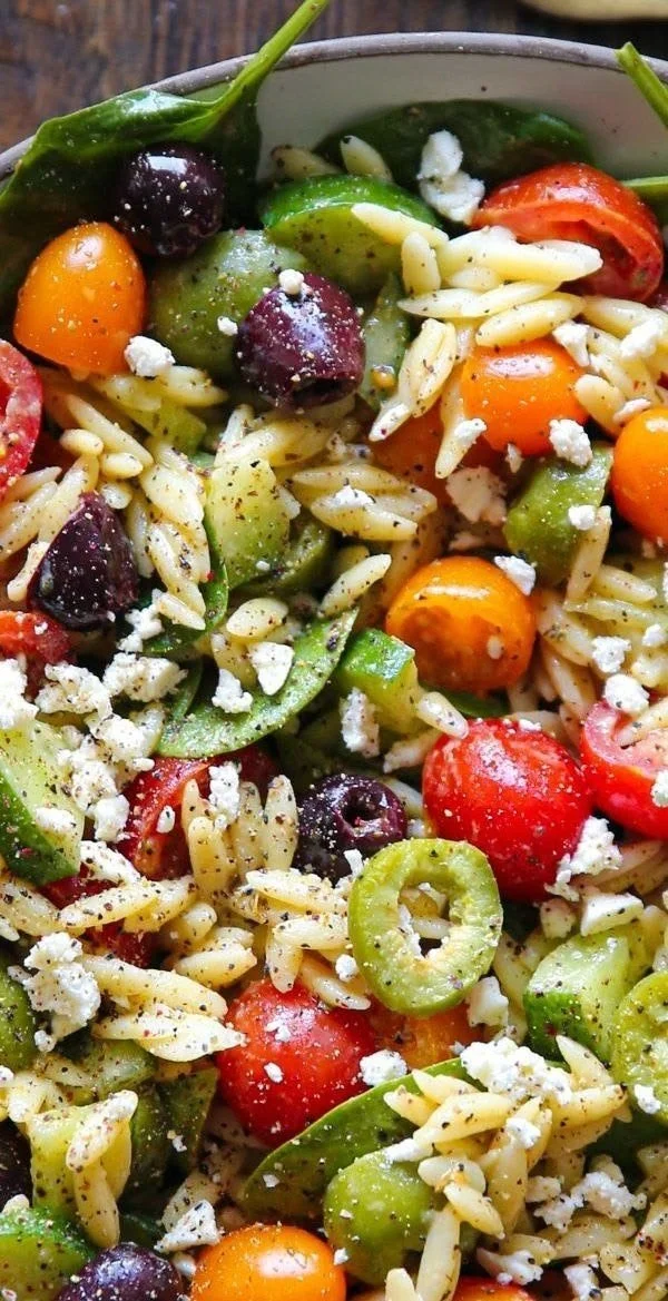 Colorful orzo salad with cherry tomatoes and feta cheese in a bowl