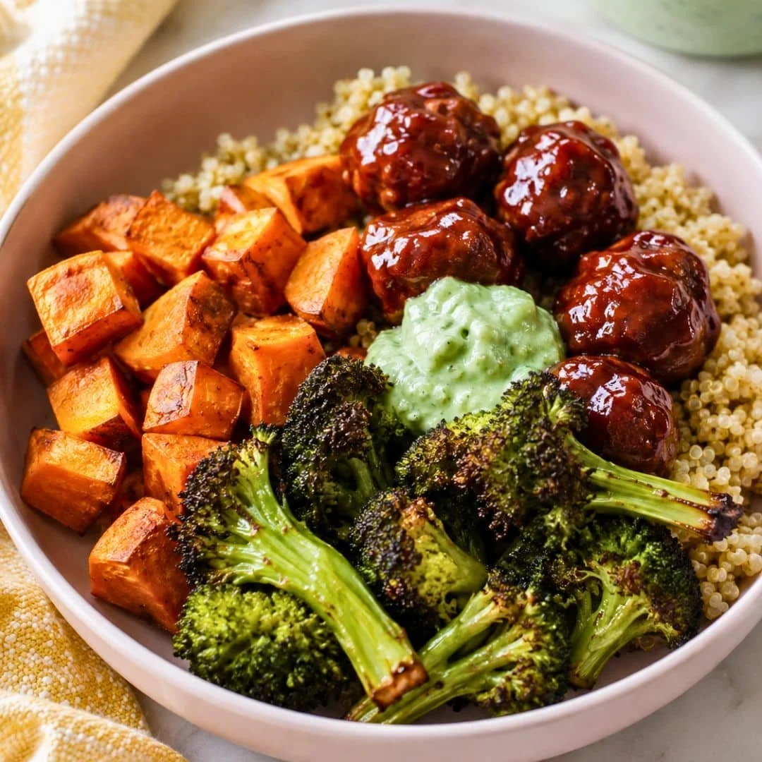 Barbecue meatball bowl topped with avocado goddess sauce in a vibrant dish