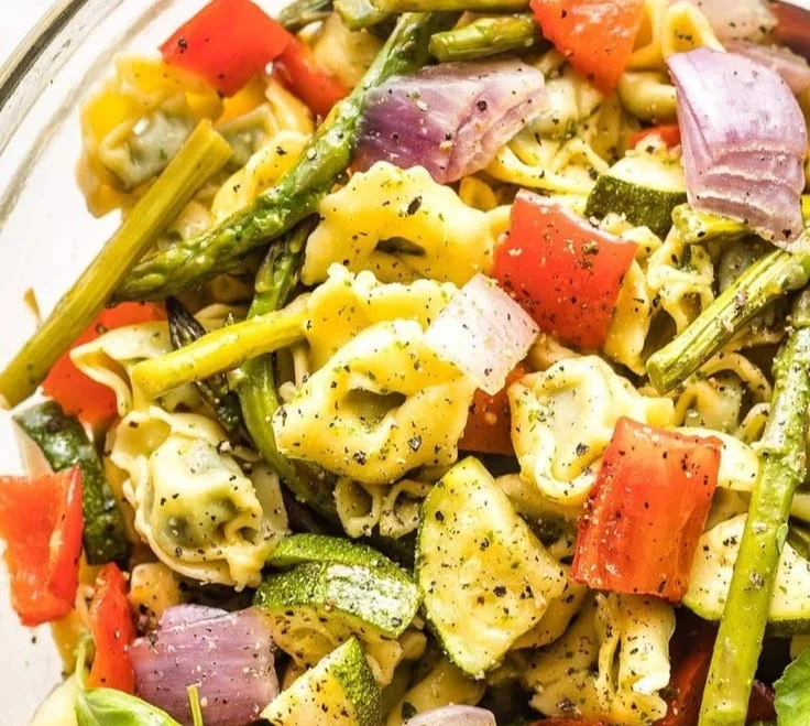 Plate of cheese-stuffed tortellini alongside colorful roasted vegetables.