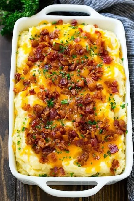Cheesy loaded mashed potato casserole topped with melted cheese and herbs.
