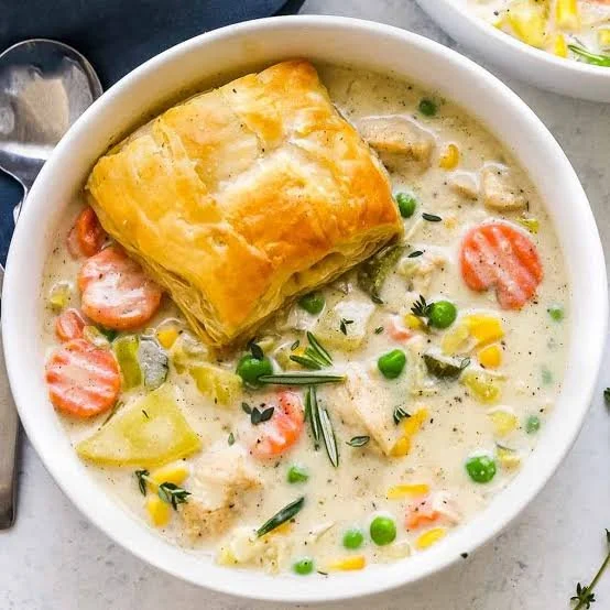 Bowl of creamy chicken pot pie soup with vegetables and herbs