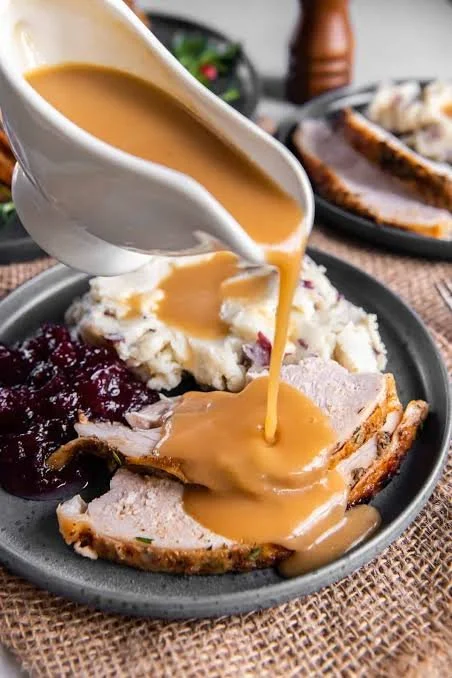Crockpot turkey and gravy served in a bowl with herbs