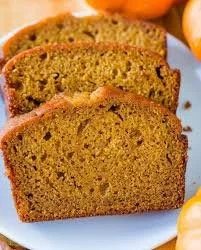 Freshly baked pumpkin bread with spices and nuts on a wooden table