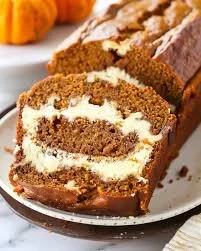 Delicious pumpkin bread topped with cream cheese frosting on a rustic wooden table