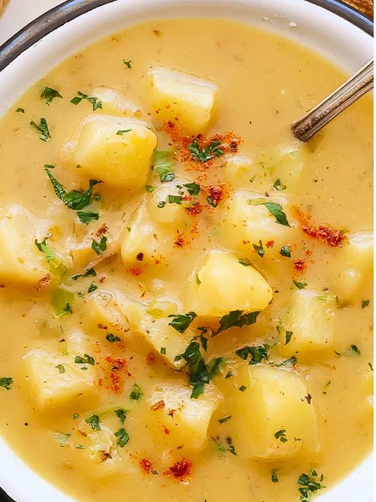 Bowl of creamy vegan potato soup topped with fresh herbs and spices